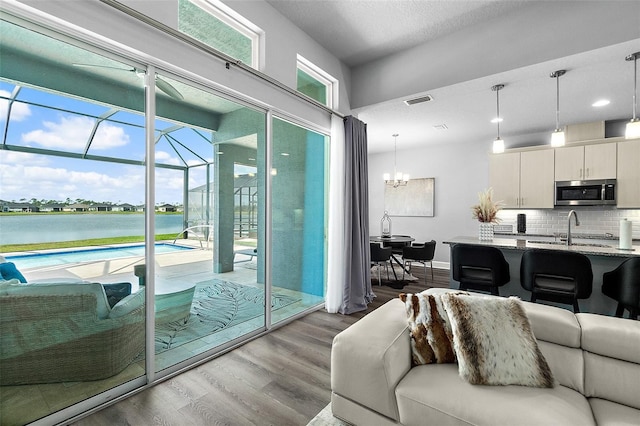165 Azure Mist Way, Daytona Beach, FL 32124 - living area with dark wood-type flooring, a chandelier, a sunroom, a water view, and baseboards
