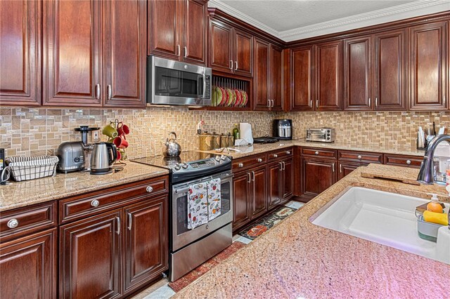 4604 Barbados Loop, Clermont, FL 34711 - kitchen with stainless steel appliances, light stone counters, a sink, decorative backsplash, and ornamental molding