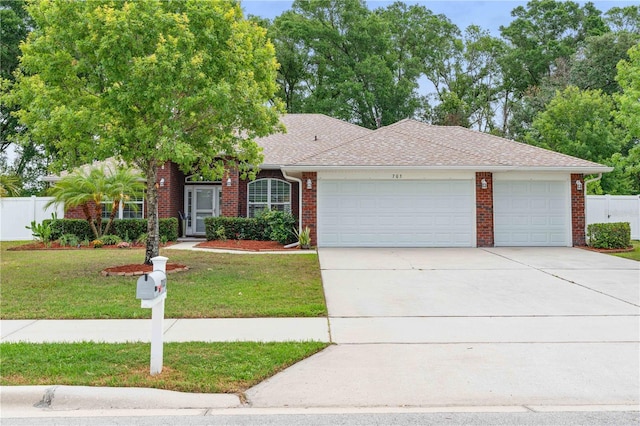 703 Elkhorn Fern Ln, Deland, FL 32720 - view of front of house featuring an attached garage, brick siding, driveway, and roof with shingles
