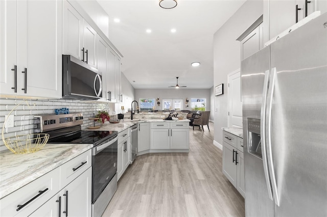 1738 Palm Rd, Ormond Beach, FL 32174 - kitchen featuring stainless steel appliances, a peninsula, a sink, open floor plan, and light wood-type flooring