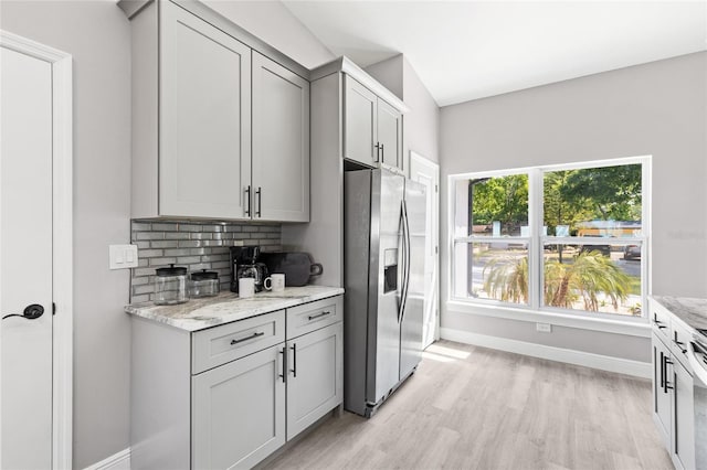 1738 Palm Rd, Ormond Beach, FL 32174 - kitchen featuring stainless steel fridge, light wood-style flooring, baseboards, decorative backsplash, and light stone counters
