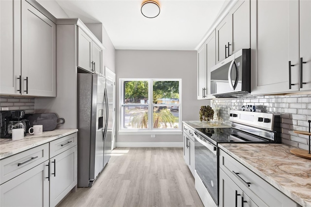 1738 Palm Rd, Ormond Beach, FL 32174 - kitchen with appliances with stainless steel finishes, light wood-style floors, decorative backsplash, baseboards, and light stone counters