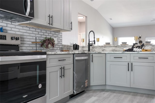 1738 Palm Rd, Ormond Beach, FL 32174 - kitchen with stainless steel appliances, light stone counters, light wood-style flooring, decorative backsplash, and a sink