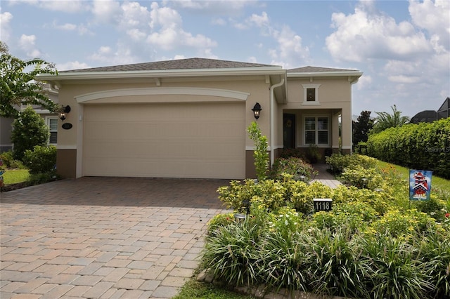 view of front facade featuring stucco siding, decorative driveway, and an attached garage