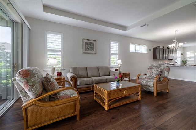 living area with a chandelier, dark wood finished floors, and baseboards