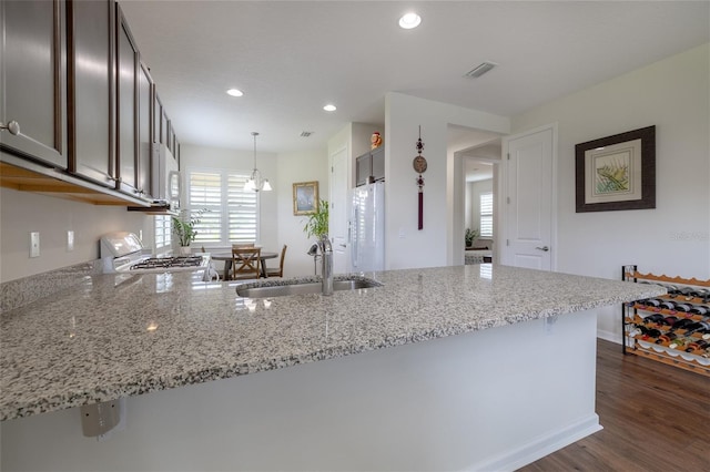kitchen with a sink, range, light stone counters, dark wood-style flooring, and recessed lighting