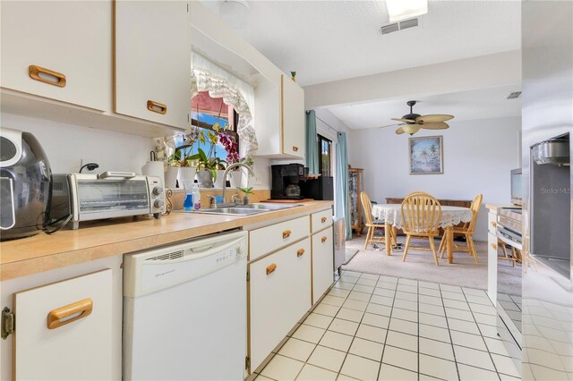 418 Falcon Ave, Edgewater, FL 32141 - kitchen featuring white dishwasher, a sink, light countertops, light colored carpet, and white cabinets