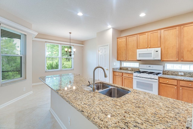kitchen with white appliances, a sink, baseboards, light stone countertops, and light tile patterned flooring