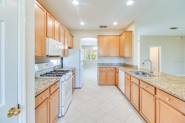 kitchen with white appliances, a sink, light brown cabinetry, light tile patterned flooring, and arched walkways
