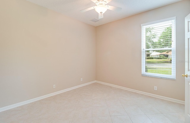 spare room with a ceiling fan, baseboards, light tile patterned floors, and a textured ceiling