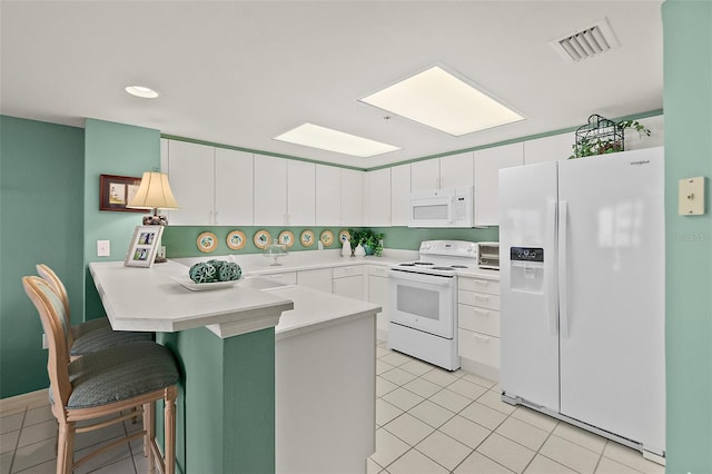 2967 S Atlantic Ave Unit 202, Daytona Beach Shores, FL 32118 - kitchen featuring white appliances, a peninsula, light tile patterned floors, a kitchen breakfast bar, and light countertops