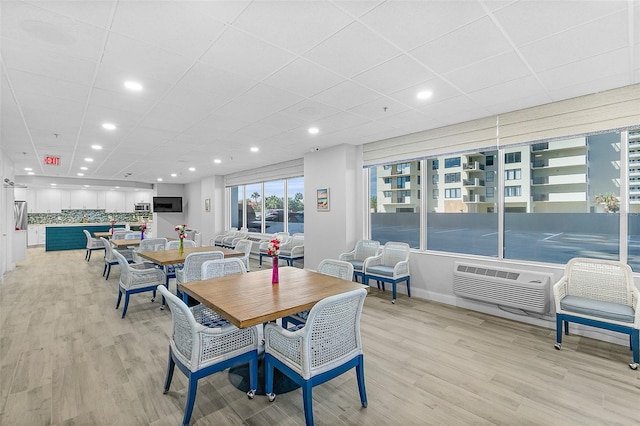 2967 S Atlantic Ave Unit 202, Daytona Beach Shores, FL 32118 - dining area featuring light wood-style floors, recessed lighting, a wall unit AC, a drop ceiling, and baseboards