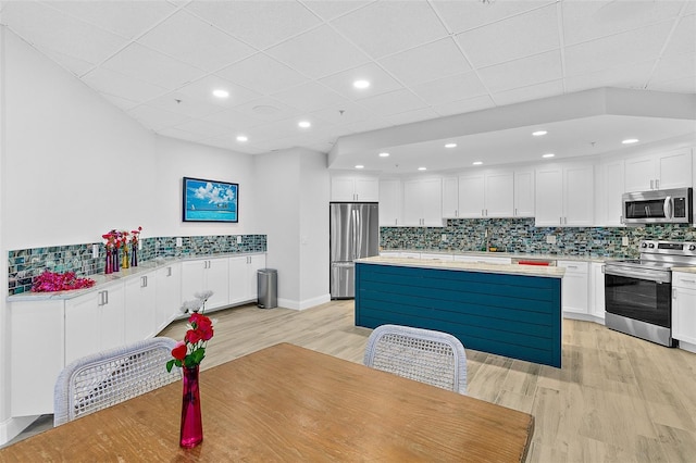 2967 S Atlantic Ave Unit 202, Daytona Beach Shores, FL 32118 - kitchen featuring appliances with stainless steel finishes, light wood finished floors, light countertops, white cabinets, and a paneled ceiling