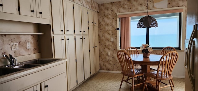 dining space featuring wallpapered walls, baseboards, and light flooring