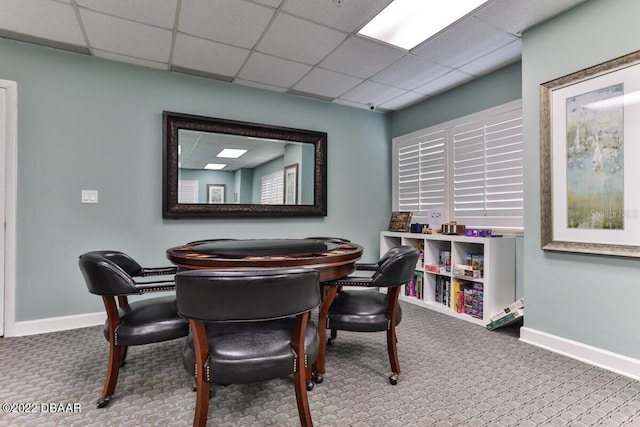 dining area with carpet floors, a paneled ceiling, and baseboards