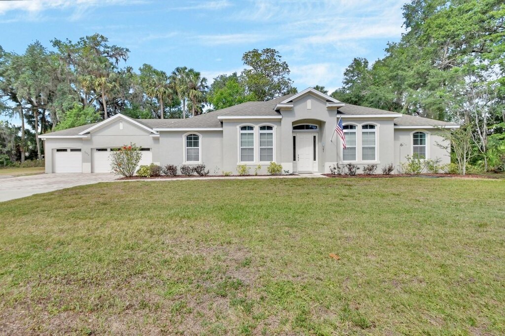 2004 Quail Hollow Dr, Deland, FL 32720 - single story home featuring a garage, concrete driveway, stucco siding, a front lawn, and roof with shingles
