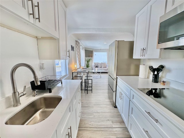 3112 S Atlantic Ave, Daytona Beach, FL 32118 - kitchen with appliances with stainless steel finishes, a sink, light wood finished floors, and white cabinets