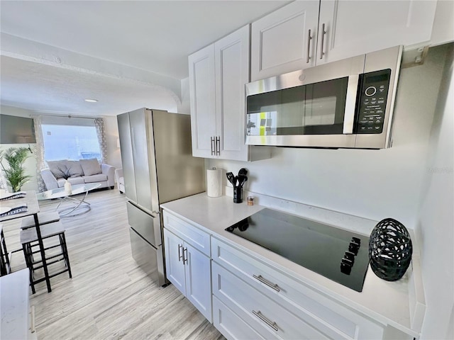 3112 S Atlantic Ave, Daytona Beach, FL 32118 - kitchen with appliances with stainless steel finishes, light wood finished floors, light countertops, open floor plan, and white cabinetry