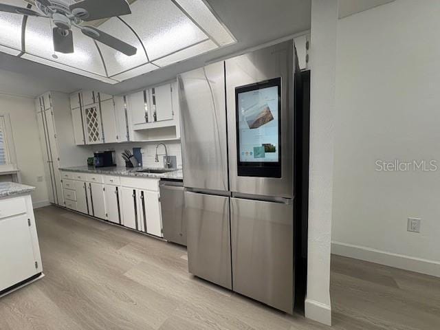 kitchen featuring appliances with stainless steel finishes, a ceiling fan, a sink, and light wood-style flooring