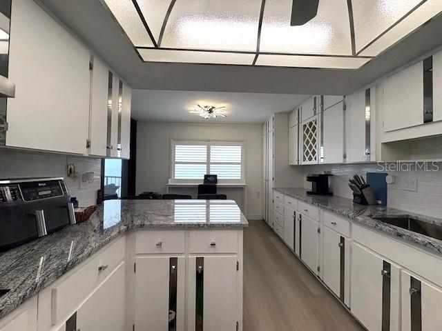kitchen with a peninsula, light wood-style floors, and white cabinetry