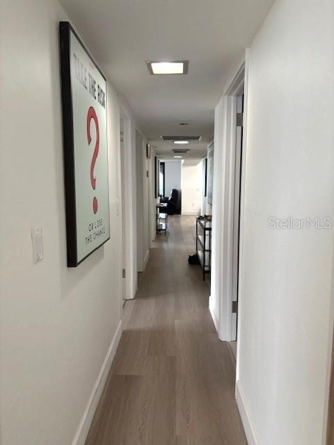 hallway featuring wood finished floors and baseboards