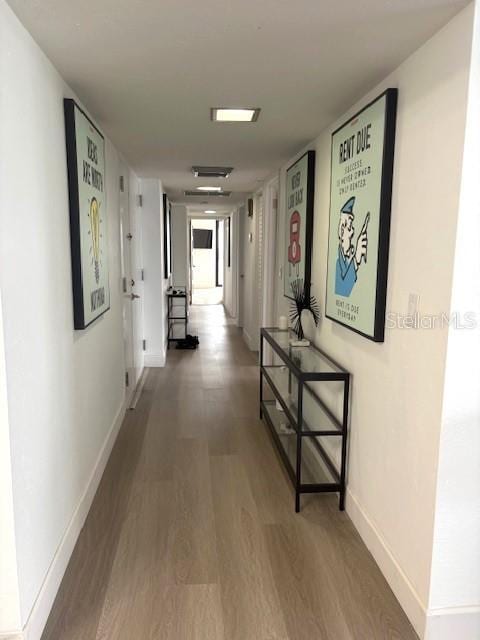 hallway featuring wood finished floors and baseboards