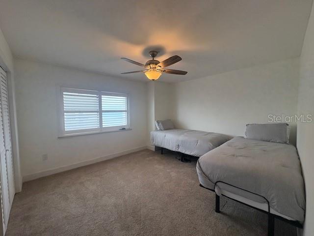 bedroom featuring light carpet, baseboards, and ceiling fan