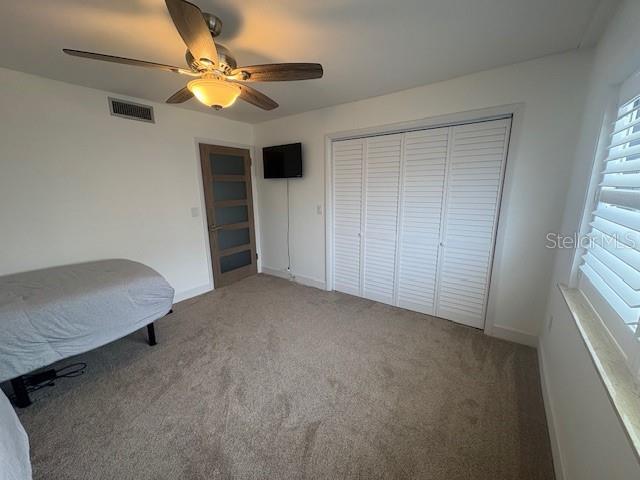 unfurnished bedroom with a closet, carpet floors, ceiling fan, and baseboards