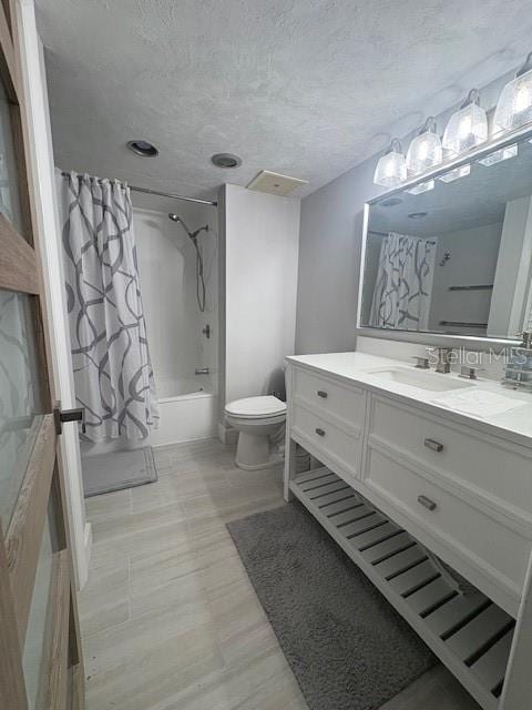 bathroom featuring toilet, shower / bathtub combination with curtain, vanity, and a textured ceiling