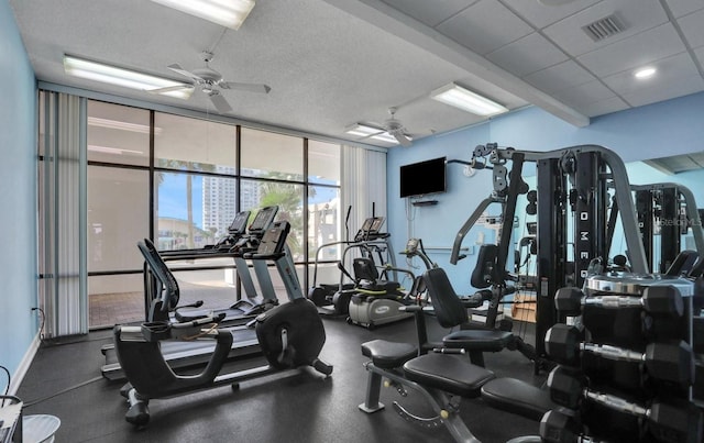 exercise room with a ceiling fan and baseboards