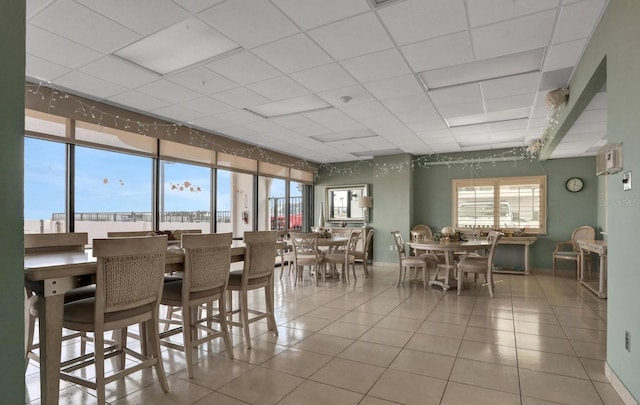 dining space with a paneled ceiling, tile patterned floors, and baseboards