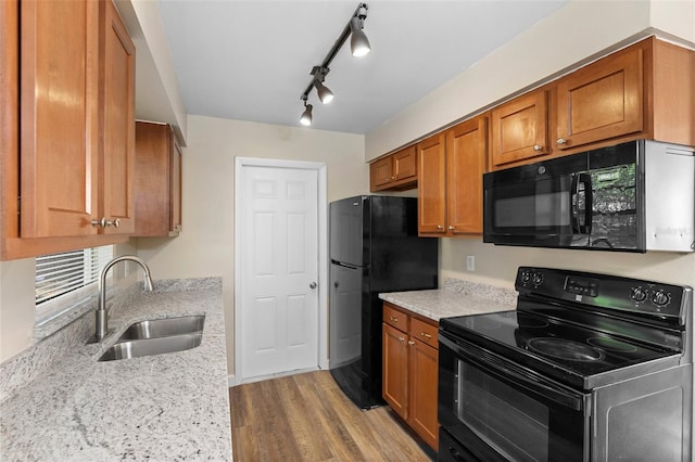 541 Northwestern Ave, Altamonte Springs, FL 32714 - kitchen featuring black appliances, a sink, brown cabinets, wood finished floors, and light stone countertops