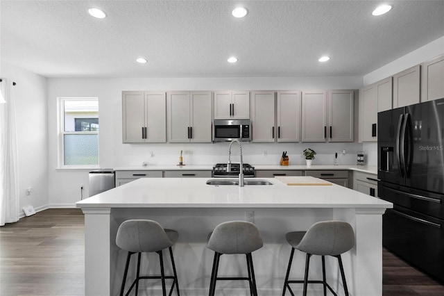 518 Briarbrook Way, Deland, FL 32724 - kitchen with stainless steel microwave, black refrigerator with ice dispenser, gray cabinetry, a breakfast bar, and recessed lighting