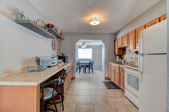 26 Ocean Shore Dr, Ormond Beach, FL 32176 - kitchen with white appliances, arched walkways, ceiling fan, light tile patterned floors, and light countertops