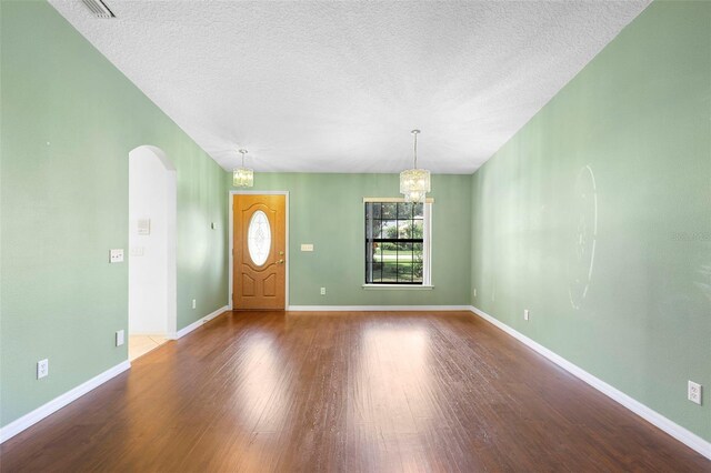 1120 W Glen Falls Rd, Deland, FL 32720 - foyer entrance with wood finished floors, a chandelier, arched walkways, a textured ceiling, and baseboards
