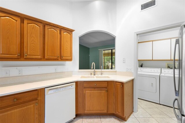 1120 W Glen Falls Rd, Deland, FL 32720 - kitchen featuring white dishwasher, a sink, washing machine and clothes dryer, arched walkways, and brown cabinets