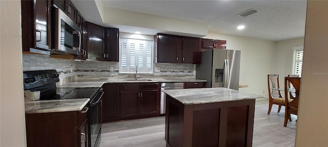 1621 Anniston Ave, Daytona Beach, FL 32117 - kitchen featuring appliances with stainless steel finishes, a sink, tasteful backsplash, a center island, and light wood-style flooring