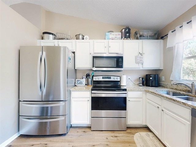 2978 Greynolds St, Deltona, FL 32738 - kitchen with appliances with stainless steel finishes, white cabinetry, a sink, and light wood-style floors