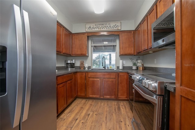 2842 English Dr, Deltona, FL 32738 - kitchen featuring appliances with stainless steel finishes, brown cabinetry, a sink, and light wood-type flooring