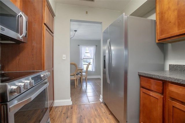 2842 English Dr, Deltona, FL 32738 - kitchen with stainless steel appliances, dark countertops, brown cabinetry, and light wood-type flooring
