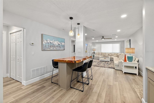 809 E 14th Ave, New Smyrna Beach, FL 32169 - kitchen featuring light wood finished floors, ceiling fan, a kitchen bar, baseboards, and recessed lighting
