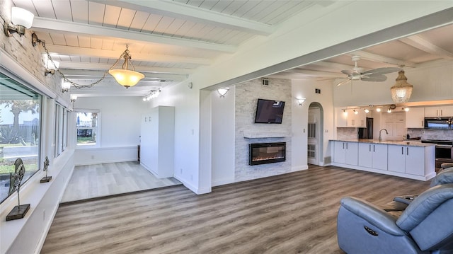 8 Ocean Dunes Dr, Ormond Beach, FL 32176 - living area with beam ceiling, wood finished floors, a stone fireplace, a ceiling fan, and baseboards