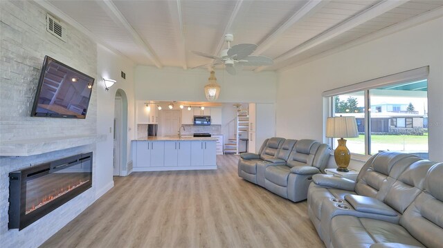 8 Ocean Dunes Dr, Ormond Beach, FL 32176 - living room featuring beam ceiling, light wood-style floors, a ceiling fan, a fireplace, and arched walkways