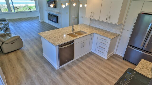 8 Ocean Dunes Dr, Ormond Beach, FL 32176 - kitchen featuring stainless steel appliances, a sink, light wood-style flooring, a peninsula, and white cabinetry