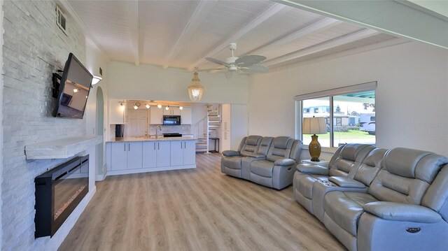8 Ocean Dunes Dr, Ormond Beach, FL 32176 - living room featuring a stone fireplace, beamed ceiling, light wood-style flooring, a ceiling fan, and stairs