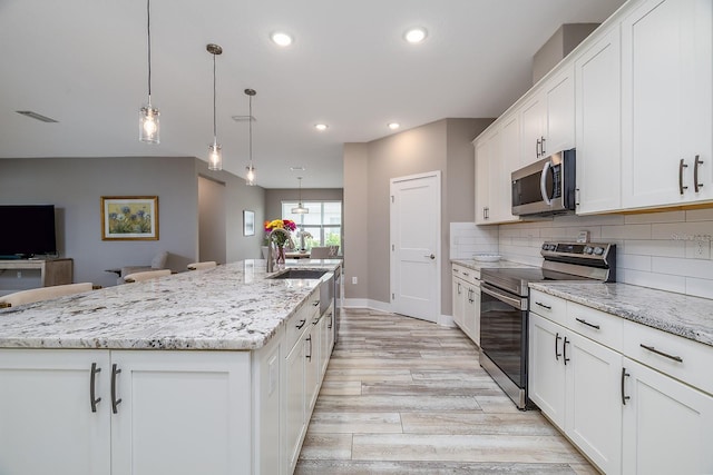 3026 Adrian Dr, Ormond Beach, FL 32174 - kitchen with appliances with stainless steel finishes, light wood finished floors, a kitchen island with sink, recessed lighting, and a sink