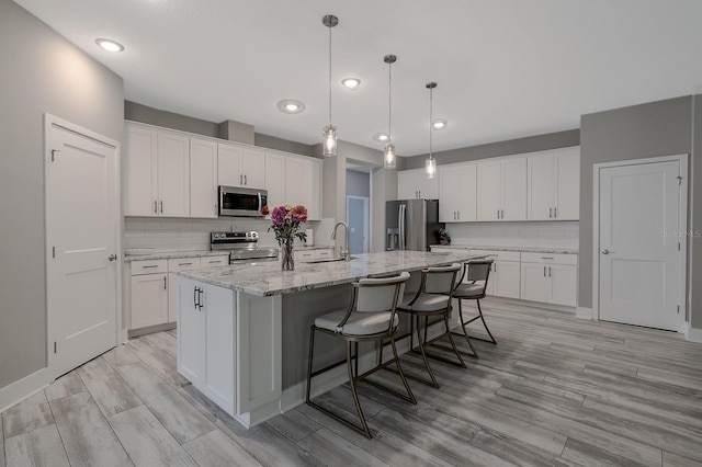3026 Adrian Dr, Ormond Beach, FL 32174 - kitchen featuring appliances with stainless steel finishes, a center island with sink, backsplash, light wood finished floors, and recessed lighting