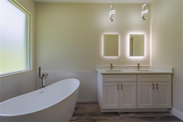 248 S Virginia Ave, Deland, FL 32724 - full bathroom featuring wood finished floors, tile walls, a freestanding tub, double vanity, and a wainscoted wall
