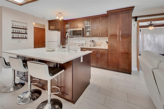 953 Tulip St, Deltona, FL 32725 - kitchen with white appliances, a breakfast bar, light countertops, glass insert cabinets, and backsplash