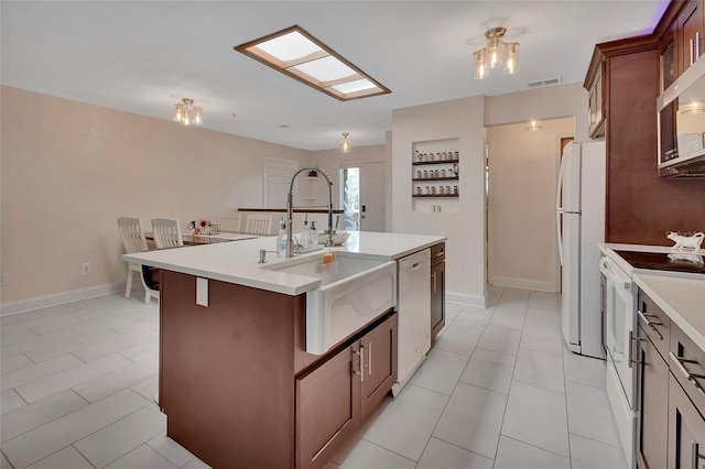 953 Tulip St, Deltona, FL 32725 - kitchen with white appliances, a sink, light countertops, a center island with sink, and baseboards